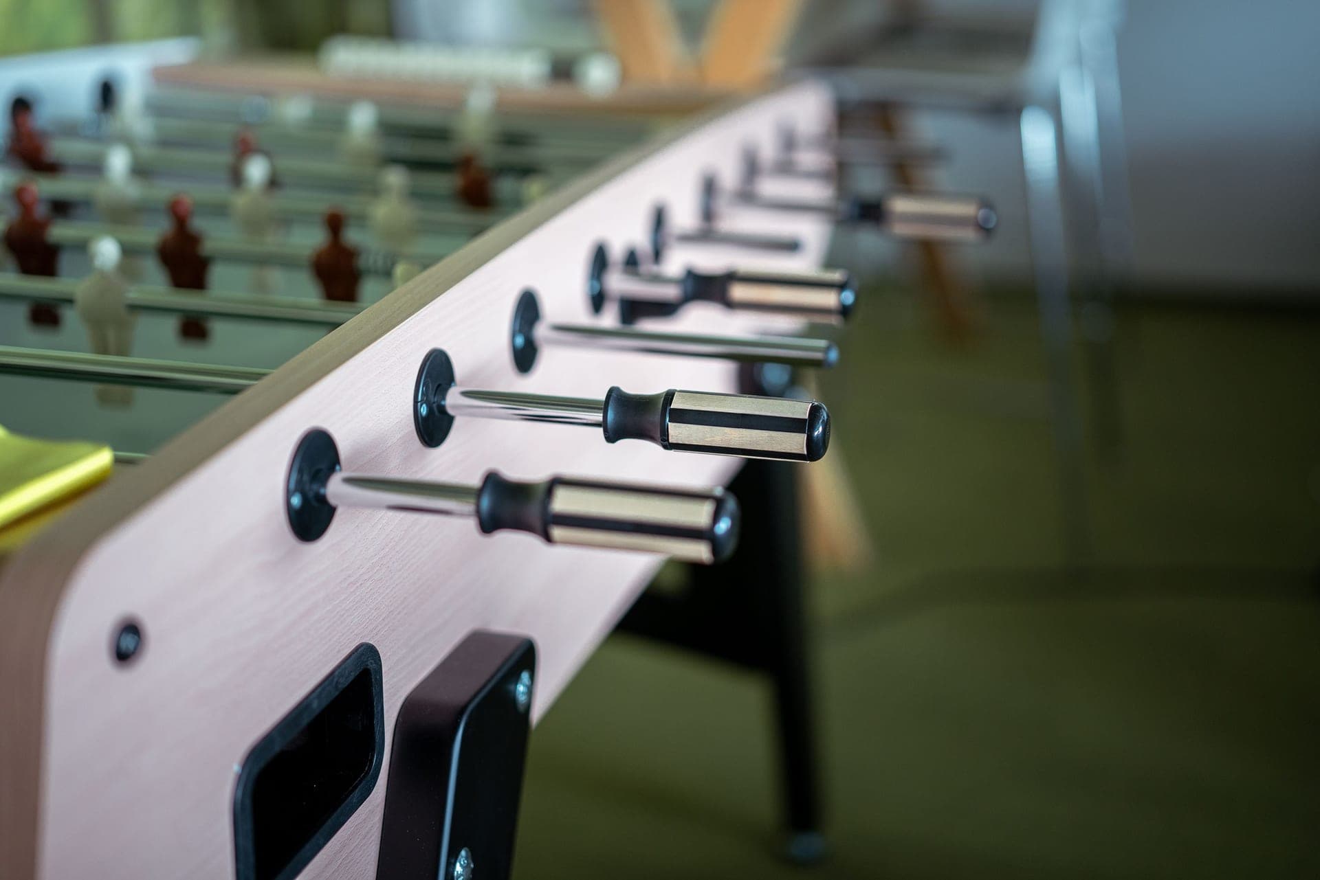 A foosball table with chrome rods in a home game room